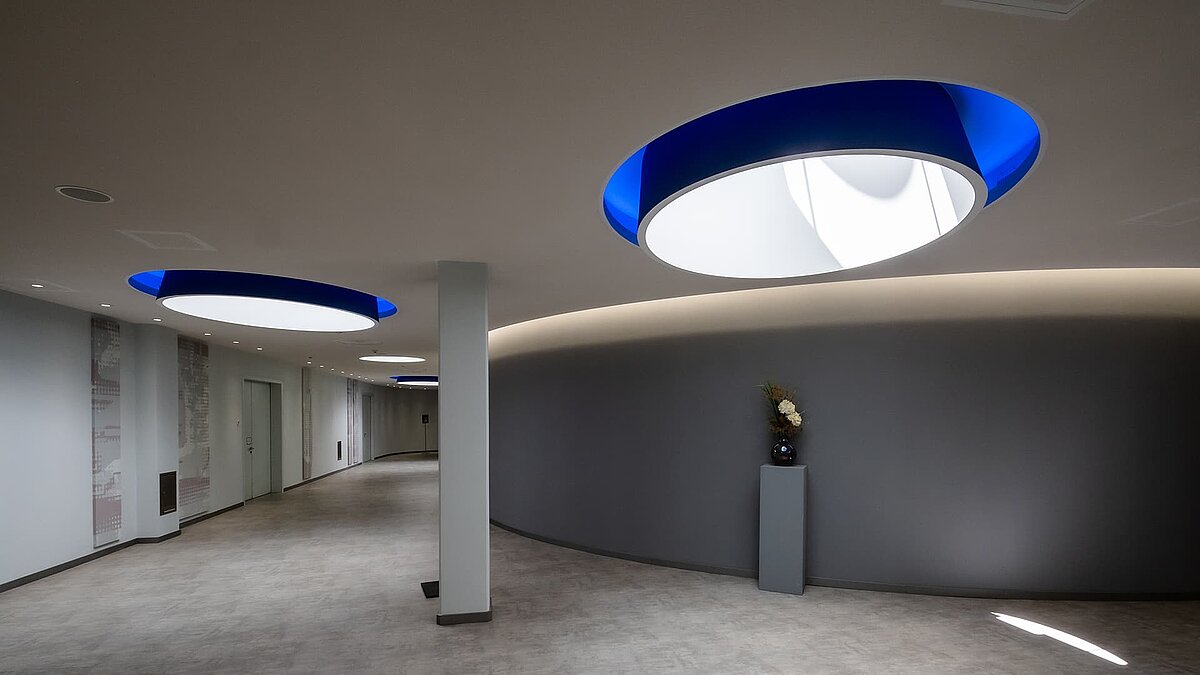 Moderner Flur im Vogel-Convention-Center in Würzburg mit runden Oberlichtern und blauen Akzenten.