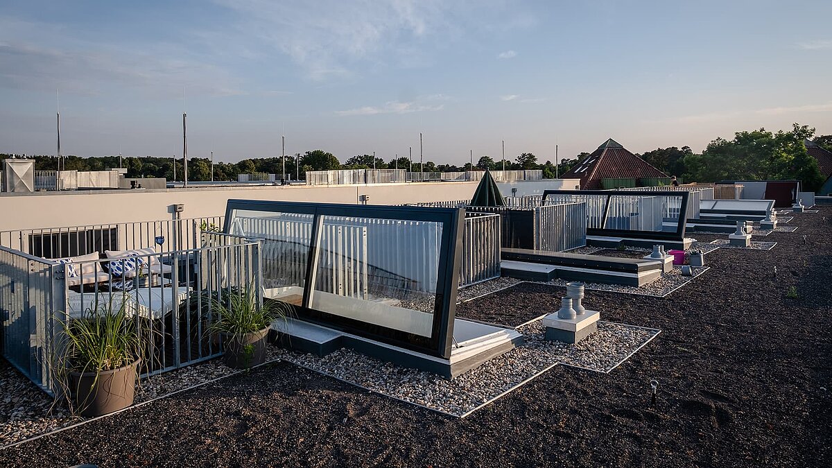 Flachdach mit Ausstiegen und privaten Terrassen am Townhouse Berlin bei Sonnenuntergang.