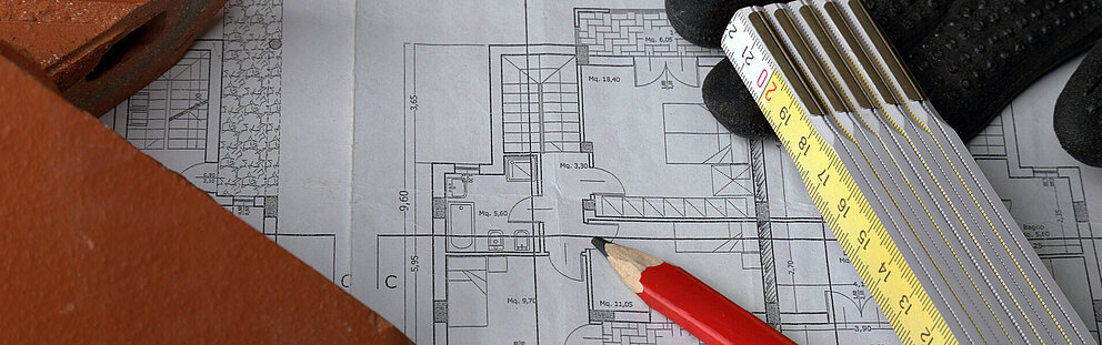 Grundriss mit Bleistift und Zollstock auf Bauplänen Architektur Grundriss mit rotem Bleistift, gelbem Zollstock und Arbeitshandschuhen auf technischer Zeichnung