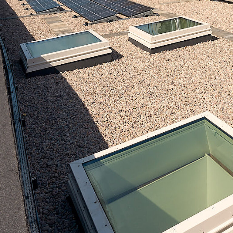 Flachdach Fenster FE Passivhaus+ auf einem Flachdach mit mehreren rechteckigen Tageslichtelementen für maximale Energieeffizienz und natürlichen Lichteinfall.