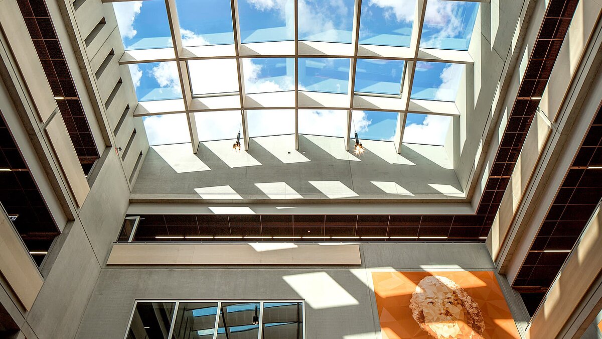 Blick auf die Glasdächer PR60 Passivhaus von LAMILUX im Willibald-Gluck-Gymnasium in Neumarkt mit blauen Himmel und Wolken.