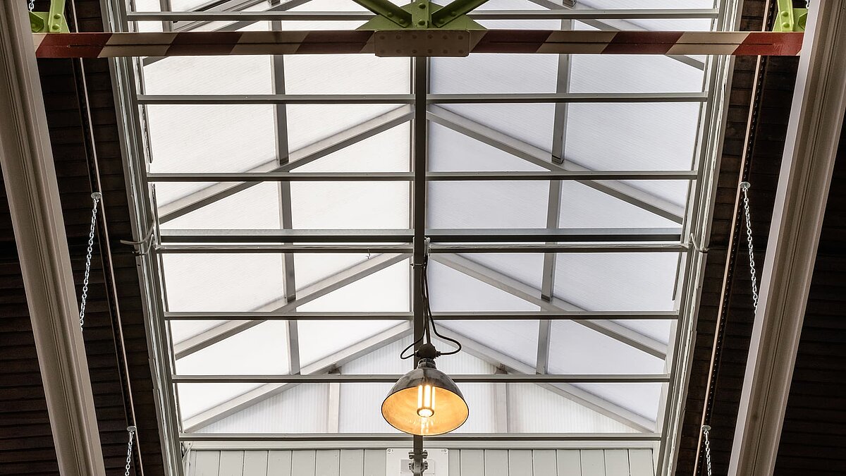 Detailansicht eines modernen Oberlichts in der Eventhalle Zündmagnet in Wurzen mit Stahlträgern und einer zentralen Hängeleuchte.