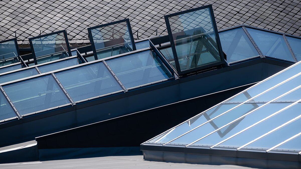 Detailansicht des das LAMILUX Glasdach PR60 am Outlet Center Selb mit geöffneten Lüftungselementen und reflektierender Oberfläche.