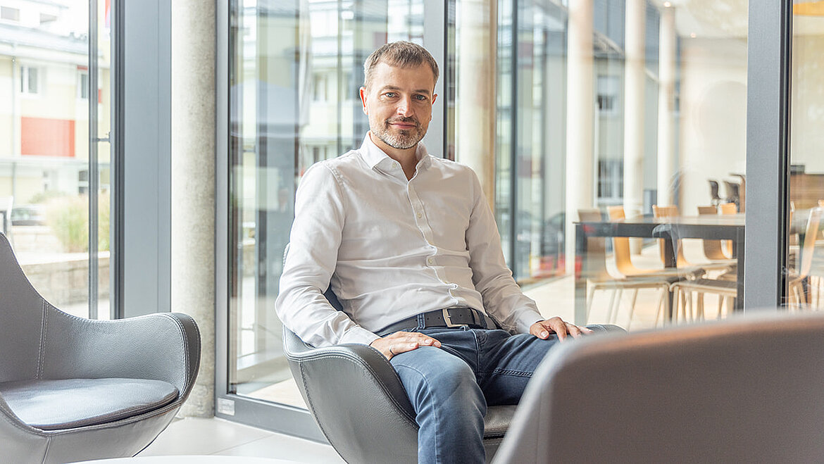 Mann sitzt in modernem und Loungebereich mit Tageslicht