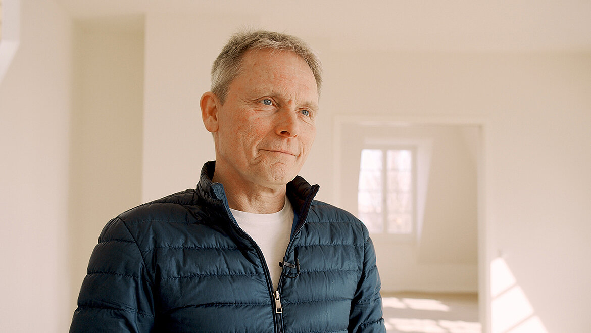 Mann steht in hellem Innenraum und spricht