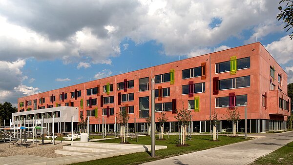 Außenansicht des Willibald-Gluck-Gymnasiums in Neumarkt mit farbenfrohen Fassadenelementen und modernem Design.