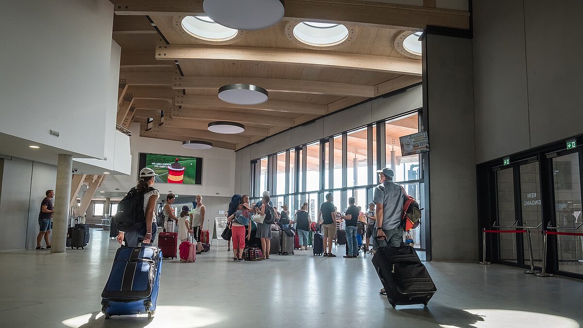 Modernes Hafenterminal Norderney mit hellem Holzdesign, runden Flachdach Fenstern und wartenden Reisenden.