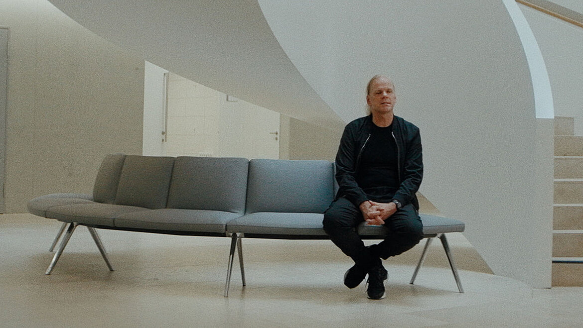 Torsten Gundlack (Architekt) sitzt auf einer Bank in vor einer Treppe