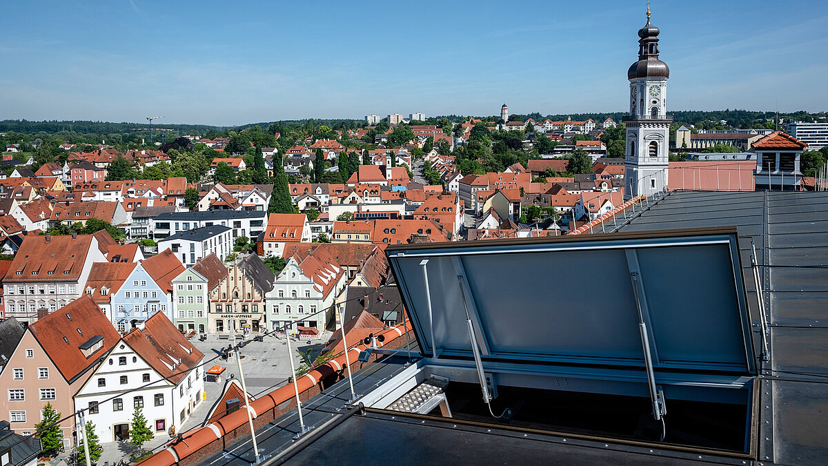 Geöffnetes Glasdach Element und im Hintergrund ist ein Kirchturm und die Stadt Freising sichtbar