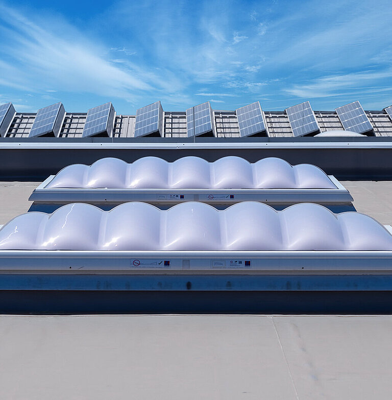 Flachdach mit mehreren Lichtkuppeln unter blauem Himmel