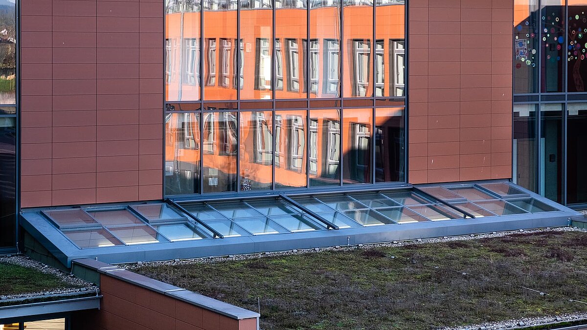 Schulzentrum Rehau mit LAMILUX Glasdach PR60 über einem begrünten Dach, das Tageslicht ins Gebäudeinnere bringt.
