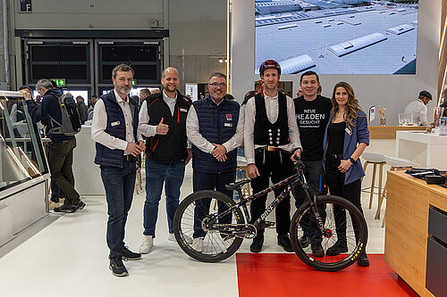 LAMILUX Mission Flachdach Team mit Fahrrad am Messestand auf Fachmesse