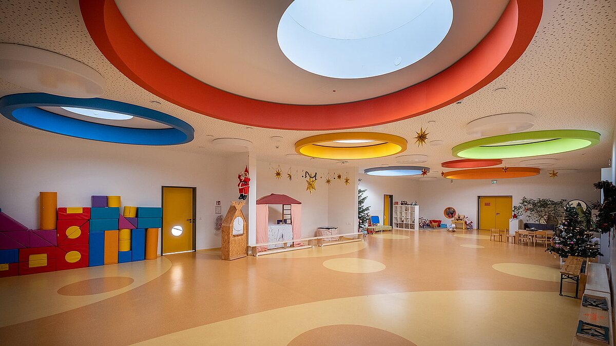 Helle, farbenfrohe Innenansicht der Kindertagesstätte Glückliche Zukunft in Sömmerda mit großen runden Oberlichtern und bunten Bausteinen.