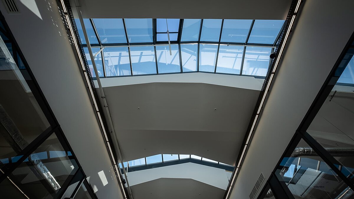 Innenansicht des LAMILUX Glasdach PR60 im Outlet Center Selb mit blauem Himmel und modernem, lichtdurchflutetem Design.