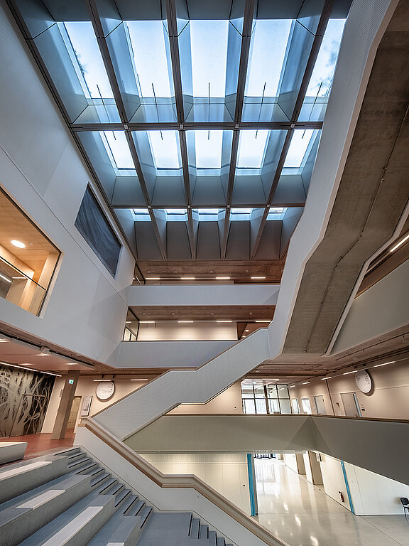 Innenaufnahme eines modernen Gebäudes mit LAMILUX Glasdach und geschwungener Treppe, Tageslicht