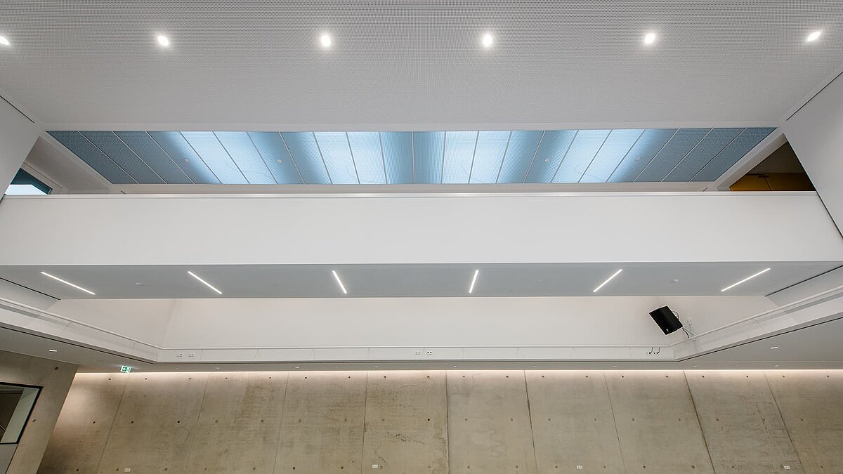 Innenansicht des Markgraf-Georg-Friedrich-Gymnasiums in Kulmbach mit großen Flachdach-Fenstern, die natürliches Licht durch die Decke in den Raum lassen.