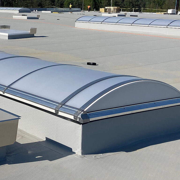 LAMILUX Lichtband B Passivhaus auf Flachdach mit bogenförmiger Verglasung zur energieeffizienten Tageslichtversorgung