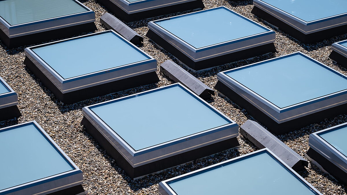 Nahaufnahme der quadratischen Oberlichter auf dem Dach des Landgerichts Weiden, umgeben von Kies.