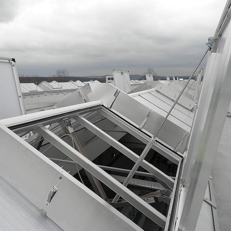 Geöffnetes LAMILUX Lichtband S RWA in Satteldachform mit aufgeklappten Flügeln und sichtbarer Tragkonstruktion