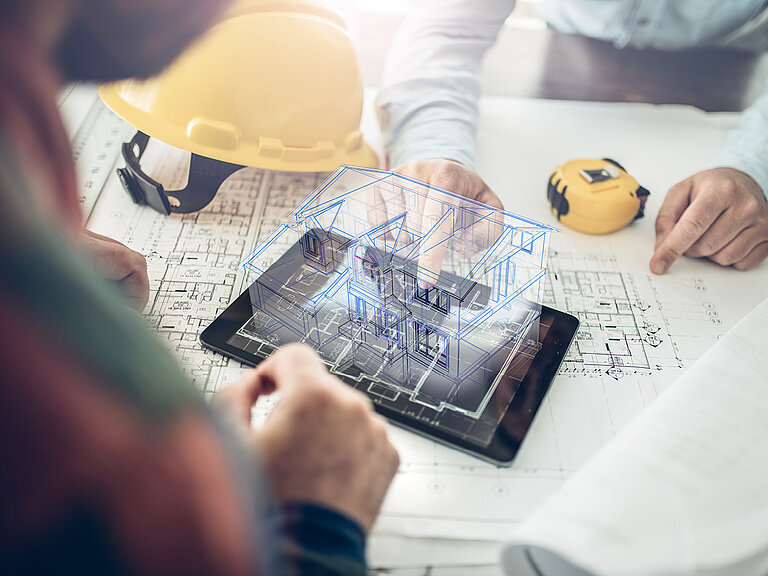 Hände von mehreren Personen, die gemeinsam an einem Tablet mit sichtbaren Bauteilen und Werkzeugen arbeiten