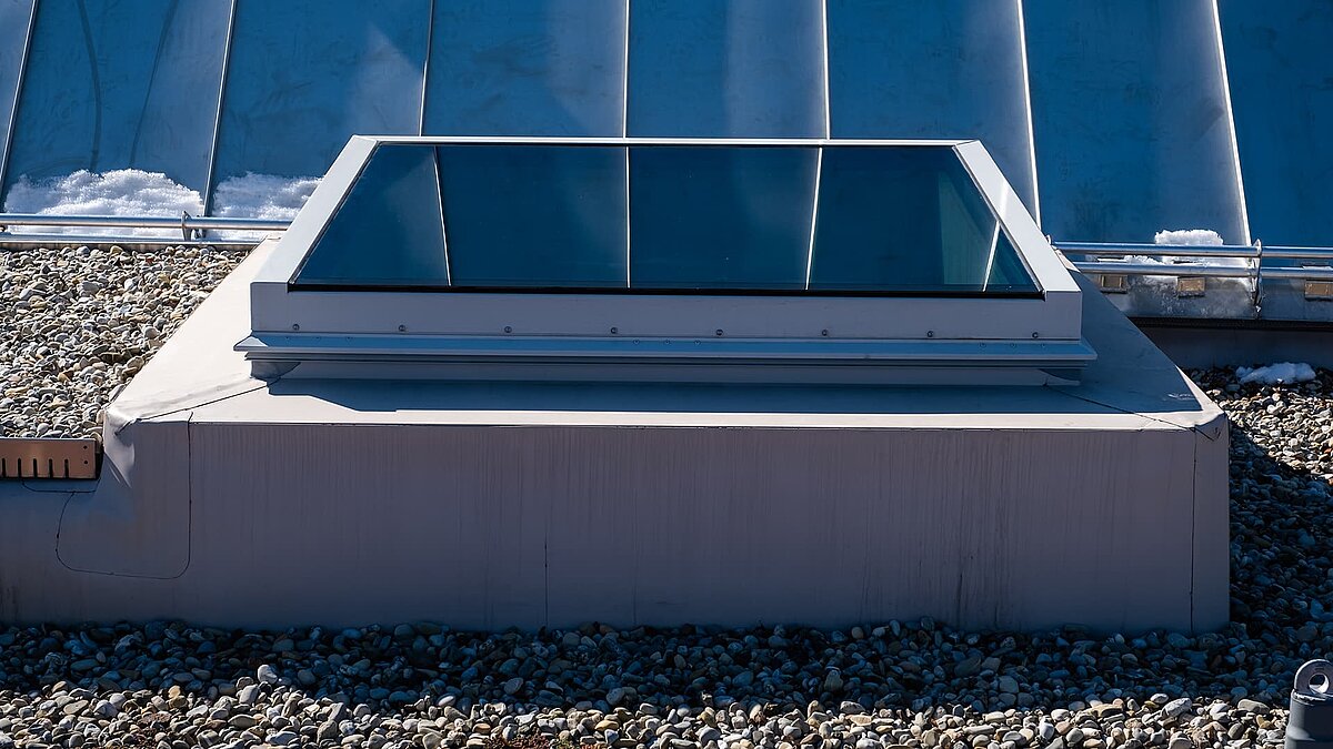 Flachdach der Kinderkrippe Waltenhofen mit modernem, rechteckigem Oberlicht und Kiesbelag.