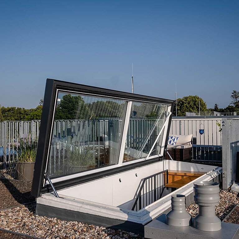Geöffneter LAMILUX Flachdach Ausstieg Komfort Swing auf Flachdach mit seitlich schwenkender Verglasung und sicherem Dachzugang