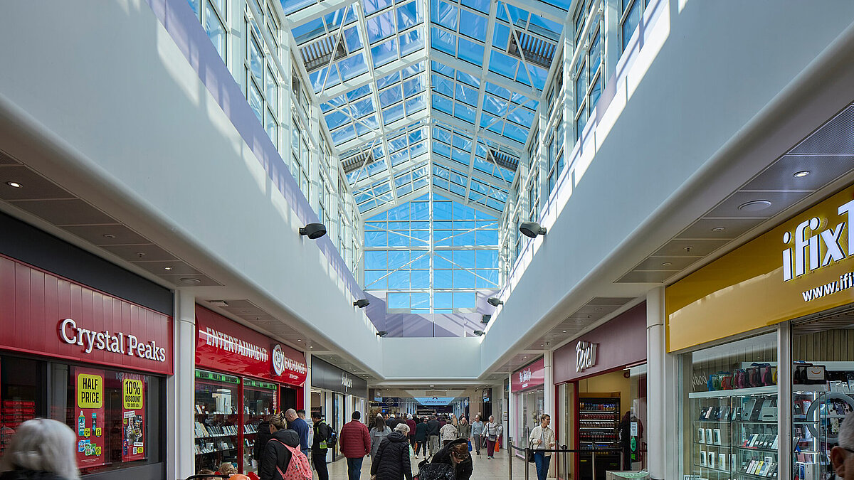 Einkaufszentrum mit Glasdach und Verkaufsständen, natürliches Licht strömt ein