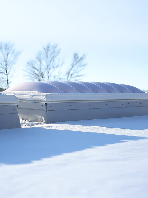 Eine F100W Lichtkuppel auf dem Dach des Gebäudes "Ab in die Box" am Diemelsee, die von Schnee bedeckt ist.