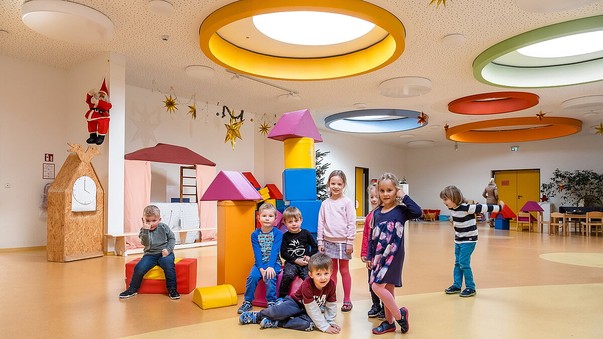Fröhliche Kinder spielen in der Kindertagesstätte Glückliche Zukunft in Sömmerda, mit bunten runden Deckenfenstern und spielerischer Einrichtung.