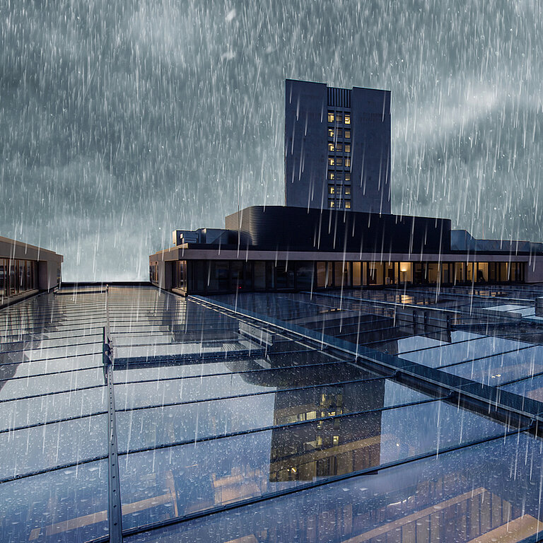 Flachdach mit verglasten Tageslichtelementen bei starkem Regen