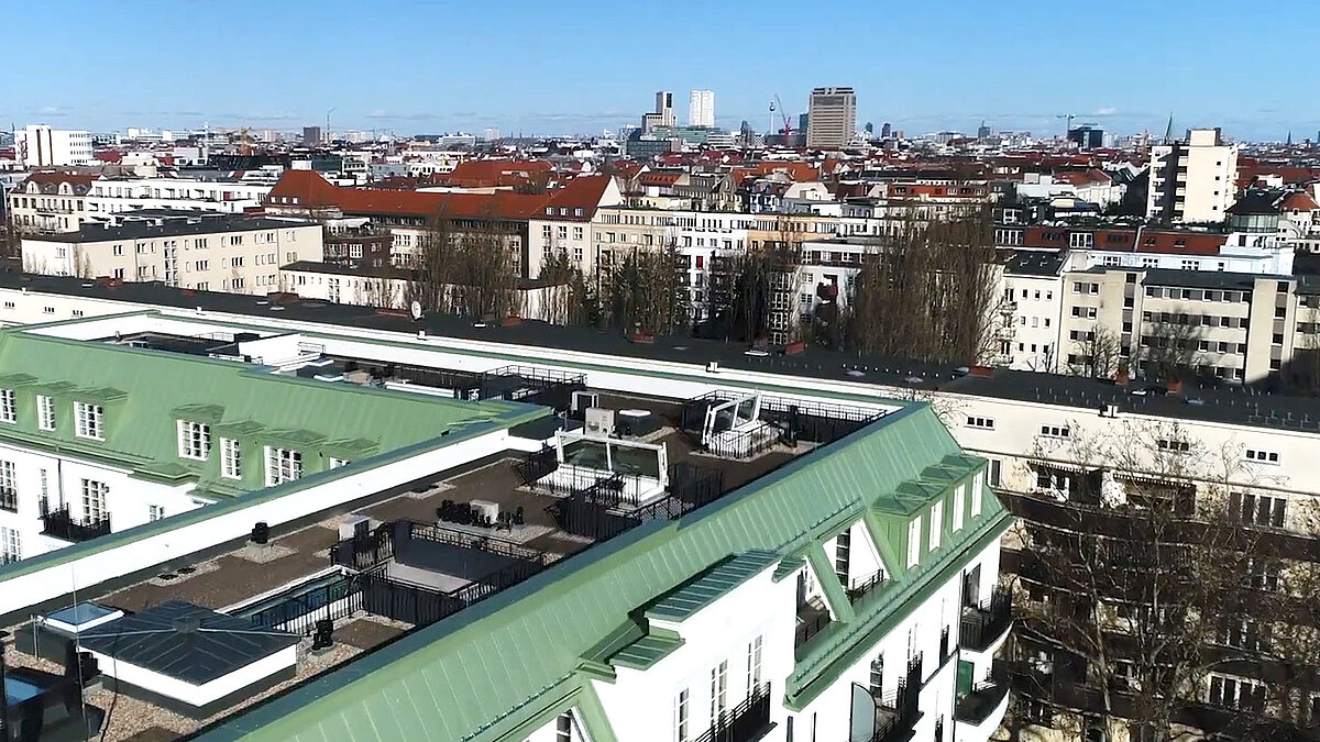 Blick auf mehrere LAMILUX Flachdach Ausstiege auf einem Dach am Hochmeisterplatz in Berlin, umgeben von Wohngebäuden und Stadtpanorama.