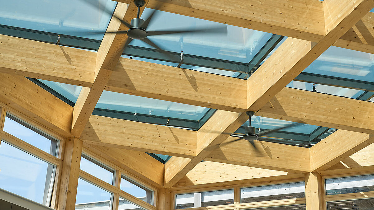 Detailansicht des LAMILUX Glasdachs PR60 mit Holztragwerk und Deckenventilatoren im Bürogebäude.