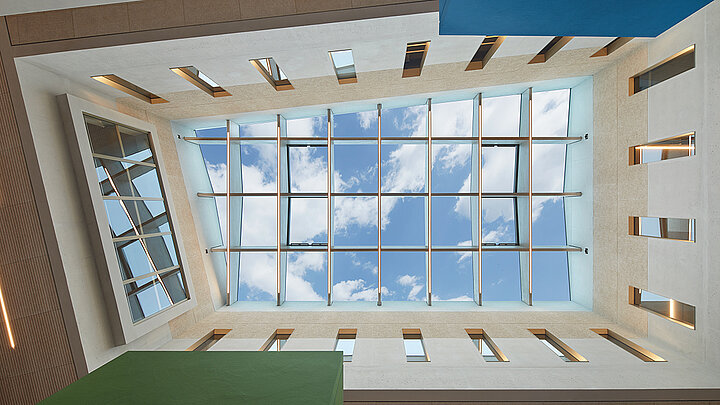 Modernes Atrium mit Glasdach und blauem Himmel