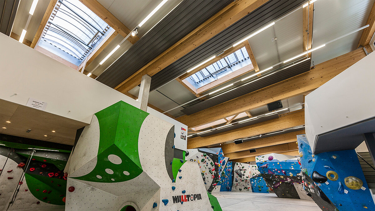 Moderne Boulderhalle mit Kletterwänden, Holzdecke und Lichtbändern