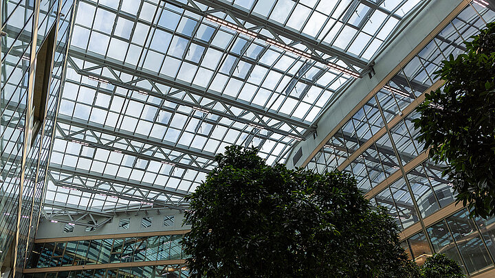 Modernes Atrium mit Glasdach und tropischen Pflanzen