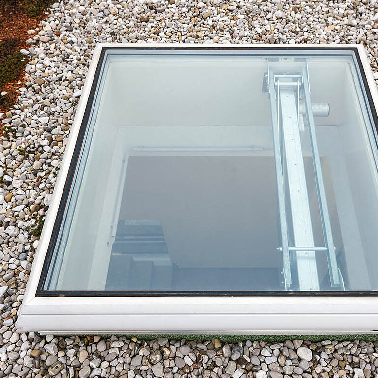 LAMILUX Flachdach Fenster F100 RWA auf Kies-Flachdach mit transparenter Verglasung und integrierter Antriebstechnik zur Rauch- und Wärmeabführung