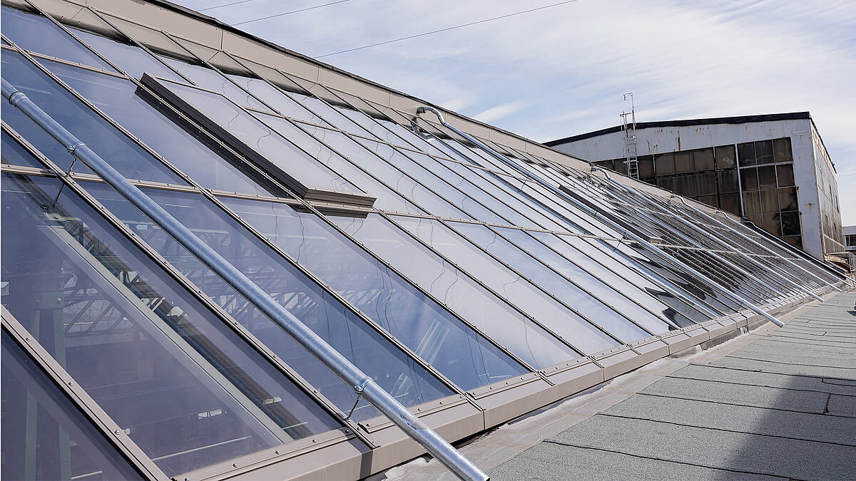 Modernes Glasdach der Factory Campus in Düsseldorf mit reflektierendem Himmel.