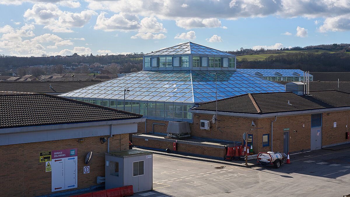 Großes, gewölbtes Glasdach mit blauer Struktur auf einem Flachdach in Industrieumgebung, Tageslicht