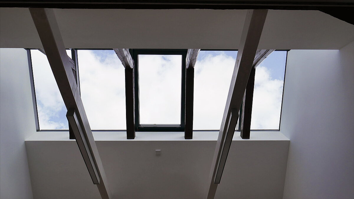 Glasdach mit Holzbalken und moderner Beleuchtung an der Leibniz-Universität Hannover, Blick auf den Himmel.
