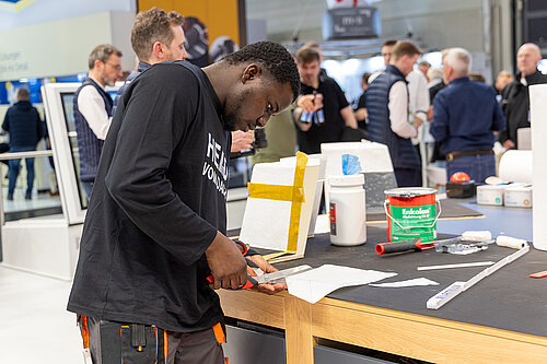 LAMILUX Mission Flachdach Teilnehmer bei Verarbeitung einer GFK Aufsatzkranzecke am Messestand