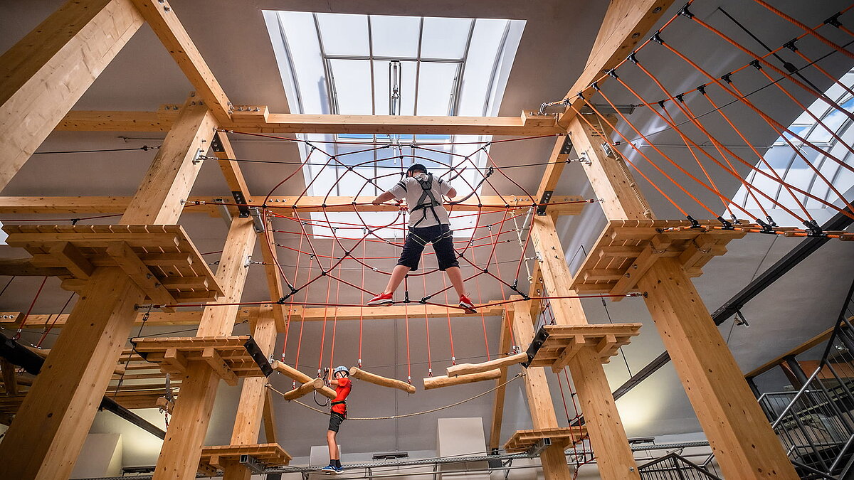 Innenansicht der Kletterhalle "Alte Brauerei" in Eisenach mit LAMILUX Lichtband B und zwei Kindern auf einem Hochseilgarten.