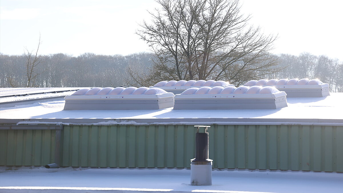 Winterliche Ansicht des Gebäudes "Ab in die Box" am Diemelsee mit schneebedeckten Lichtkuppeln F100W auf dem Dach.