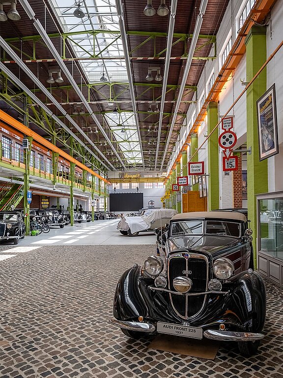 Ein Oldtimer im Vordergrund der Eventhalle Zündmagnet in Wurzen mit historischen Backsteinwänden, großen Glasfenstern und Oberlichtern.