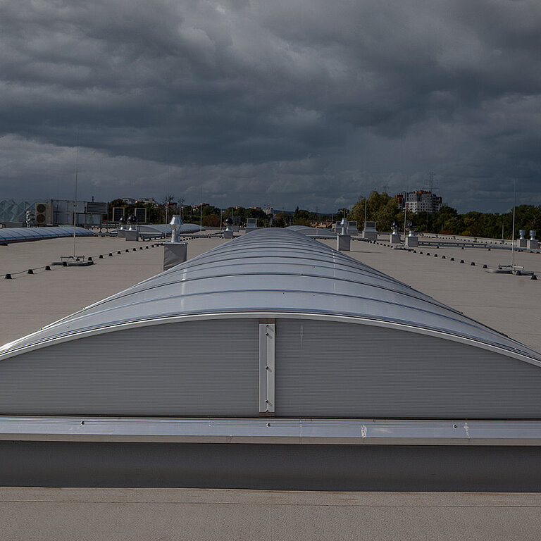 LAMILUX Lichtband auf großem Flachdach unter bewölktem Himmel zur gleichmäßigen Tageslichtversorgung