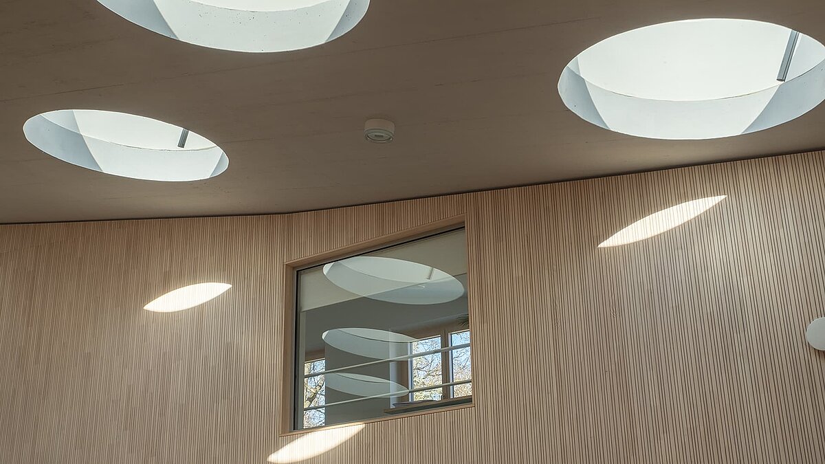 Innenansicht auf runde Flachdachfenster im Kindergarten St. Severin, die natürliches Licht in den Innenraum lenken.