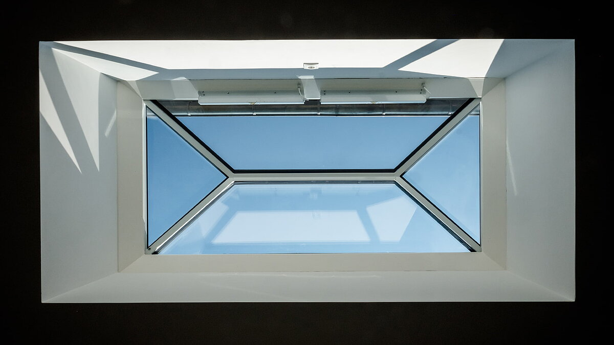 Innenansicht eines LAMILUX Flachdach Fensters FW in einem Wohnhaus in Hamburg mit klarem Blick auf den blauen Himmel.