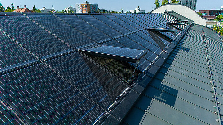 Ein langes Dach eines städtischen Gebäudes mit transparenten Solarmodulen. 