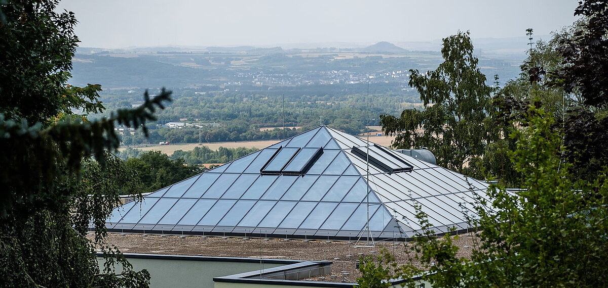 Außenansicht vom Glasdach im Zoo Neuwied mit PR60-Konstruktion umgeben von Bäumen mit Blick auf die Landschaft.