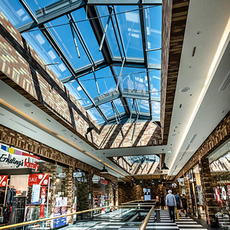 Großzügiges Einkaufszentrum mit modernem Glasdach, viel Tageslicht und offenen Galerien
