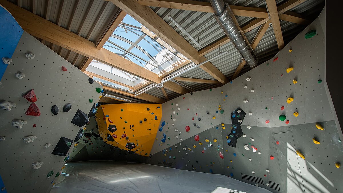 Kletterhalle im Kletterzentrum OWL mit Kletterwänden in verschiedenen Farben und einer großen Lichtkuppel für Tageslicht.